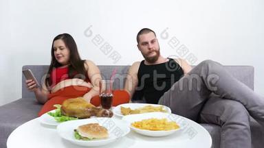 超重夫妇吃快餐，汉堡包，薯<strong>条</strong>，炸薯<strong>条</strong>和看<strong>电视</strong>。